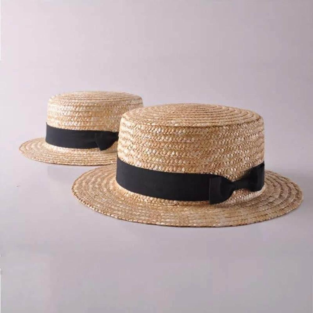 Two straw boater hats with flat tops and black ribbon bands, displayed on a plain background.