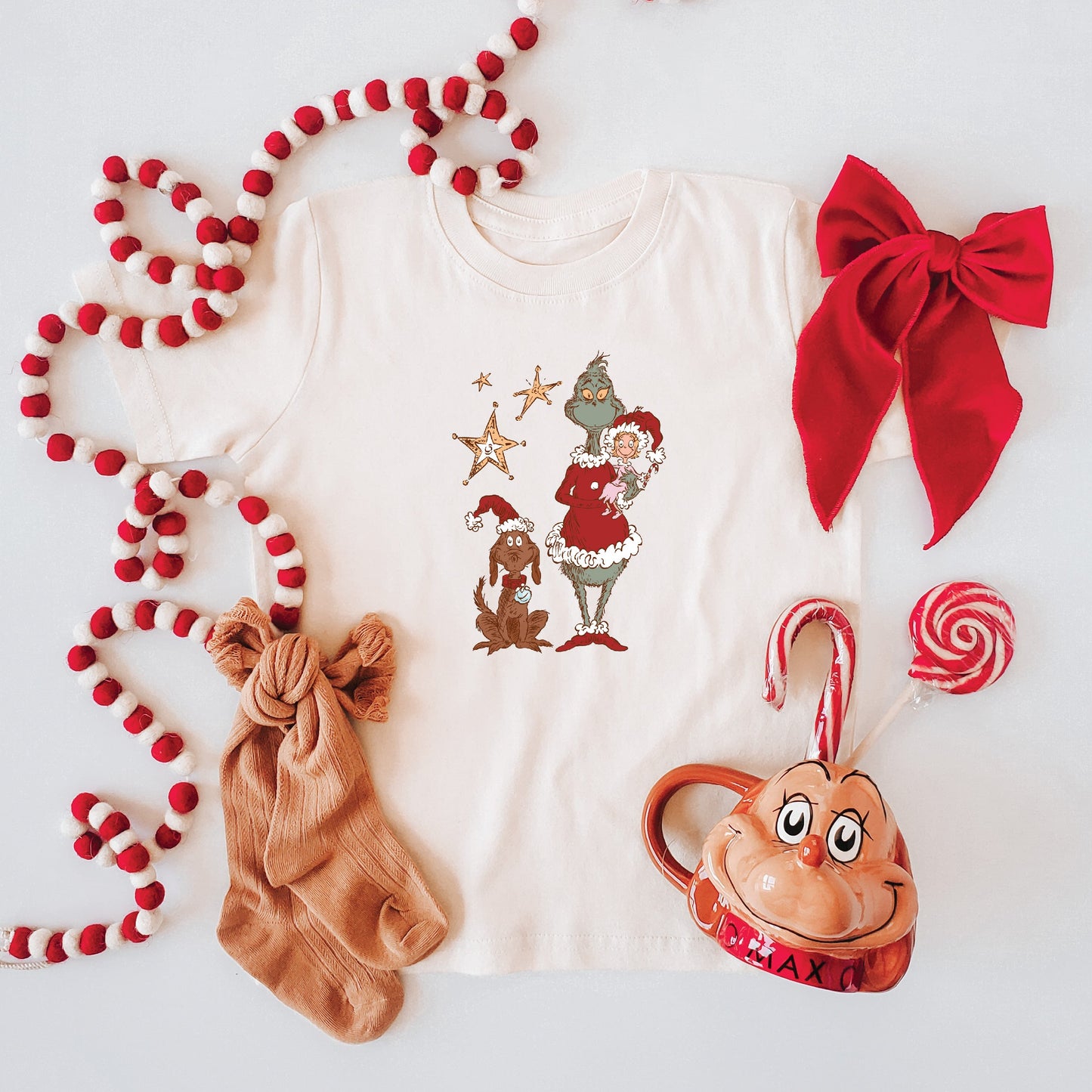 Baby outfit with shirt, socks, and mug featuring Christmas-themed graphics on a white background.