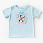Light blue kids' t-shirt with "Miss Mouse in Paris" design featuring The Mouse in a frame with Eiffel Tower, macarons, and bows.