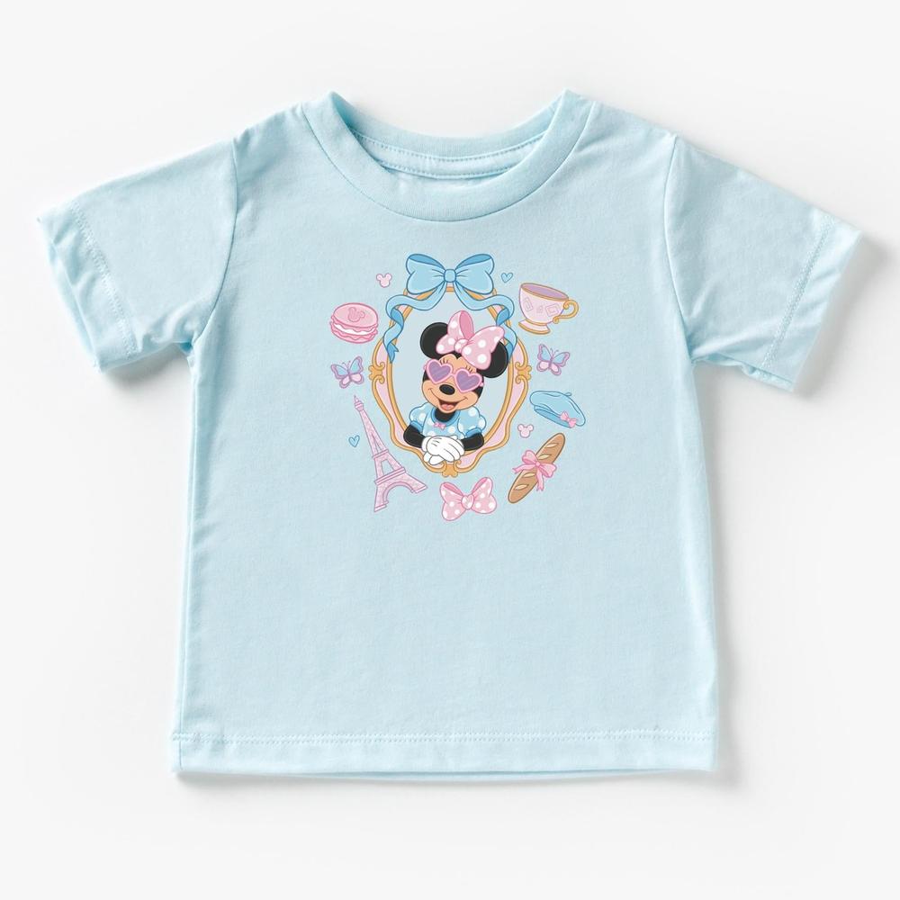 Light blue kids' t-shirt with "Miss Mouse in Paris" design featuring The Mouse in a frame with Eiffel Tower, macarons, and bows.