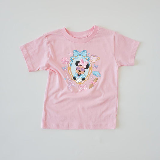 Pink kids' t-shirt with "Miss Mouse in Paris" design featuring The Mouse in sunglasses, Eiffel Tower, and macarons.