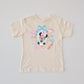 Beige unisex T-shirt with a "Miss Mouse in Paris" design featuring The Mouse, Eiffel Tower, and macarons.