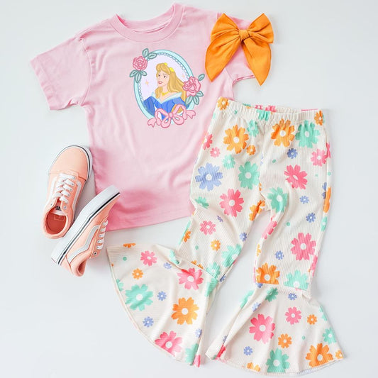 Pink Aurora T-shirt with floral bell bottoms, peach sneakers, and an orange hair bow.