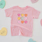 Pink baby romper with colorful heart designs surrounded by heart-shaped cards on a light gray background