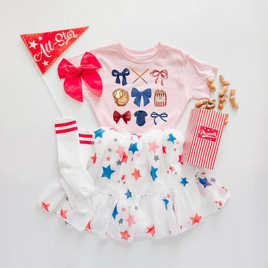 Pink kids' baseball tee with coquette bows, star skirt, striped socks, "All-Star" pennant, and peanuts.