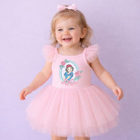 Smiling toddler in a pink ballerina dress with a Snow White graphic, tulle skirt, and a matching bow headband.