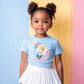Young girl in a light blue Cinderella t-shirt with pink roses, paired with a white pleated skirt.