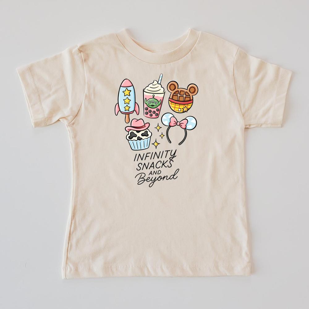 Kids' cream t-shirt with "Infinity Snacks and Beyond" text and colorful cartoon snacks like a rocket, boba, and The waffle.
