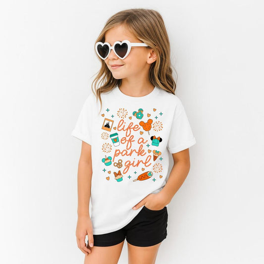 Young girl in white "Life of a Park Girl" t-shirt with colorful park icons, black shorts, and white heart sunglasses.