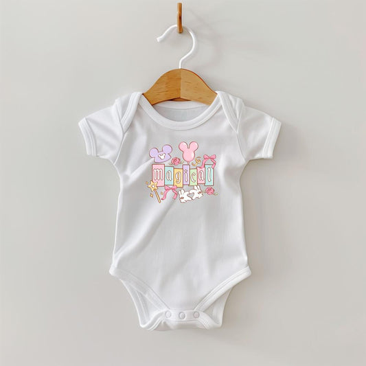 White baby onesie with "MAGICAL" in pastel blocks, mouse ears, wand, and roses.