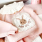 Pink knitted Snuggly Bunny Sweater with a white lace-trimmed bunny appliqué and a separate ruffled collar.