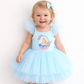 Child wearing a light blue dress with a fairy design on a white background