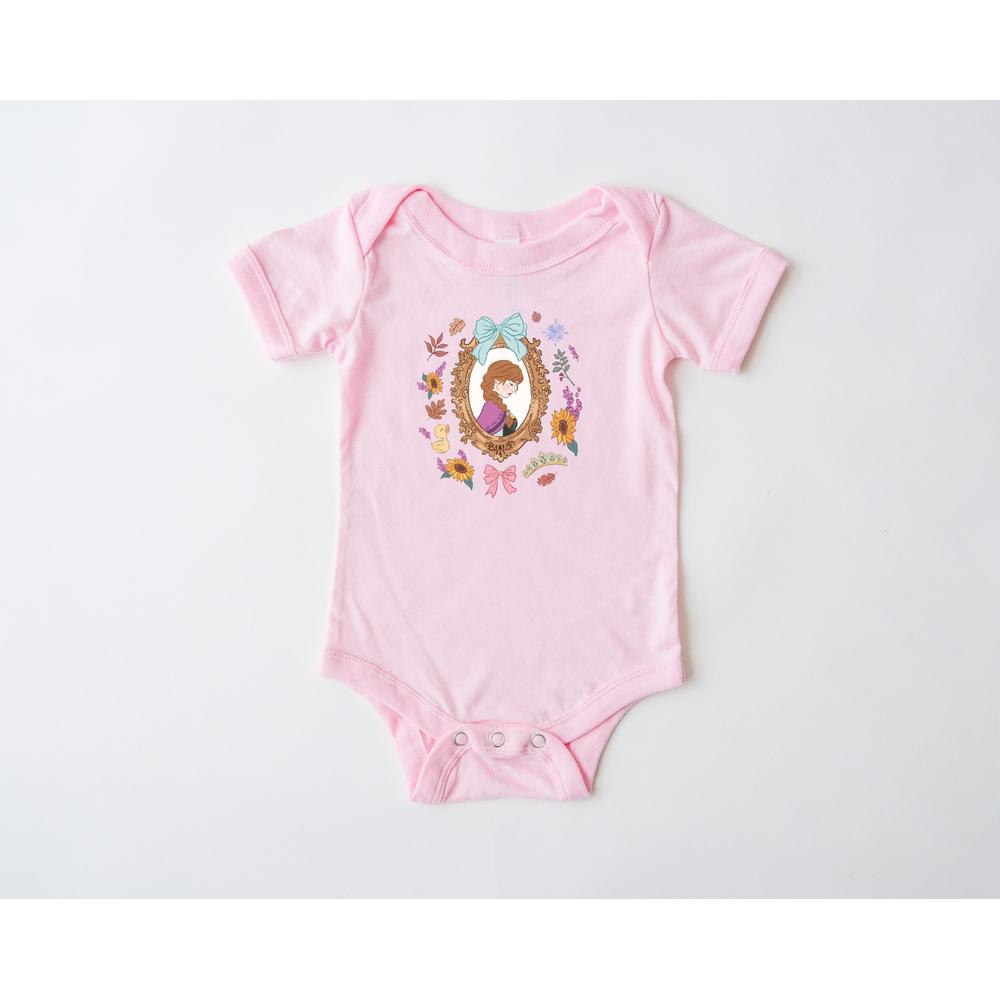 Pink infant onesie with a Wonderland character design in a gold frame surrounded by colorful flowers.