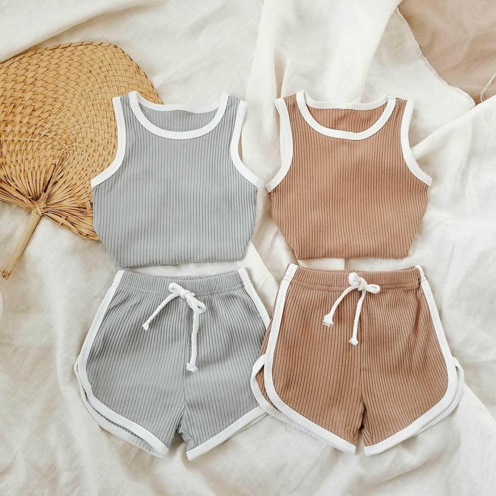 Two ribbed sleeveless children’s tank top and shorts sets in beige and gray, flat lay.