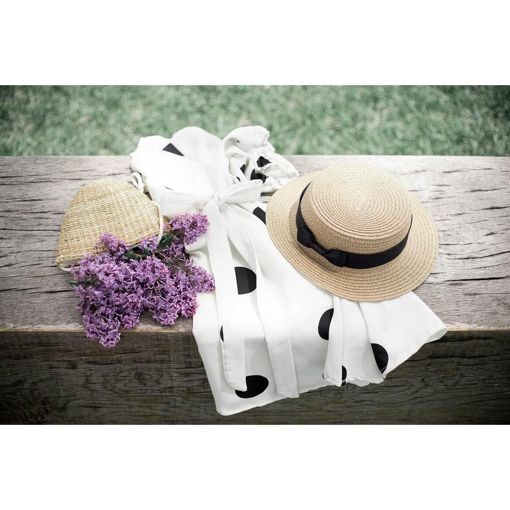 Polka dot dress, straw hat with ribbon, wicker purse, and lilac flowers on rustic wood bench
